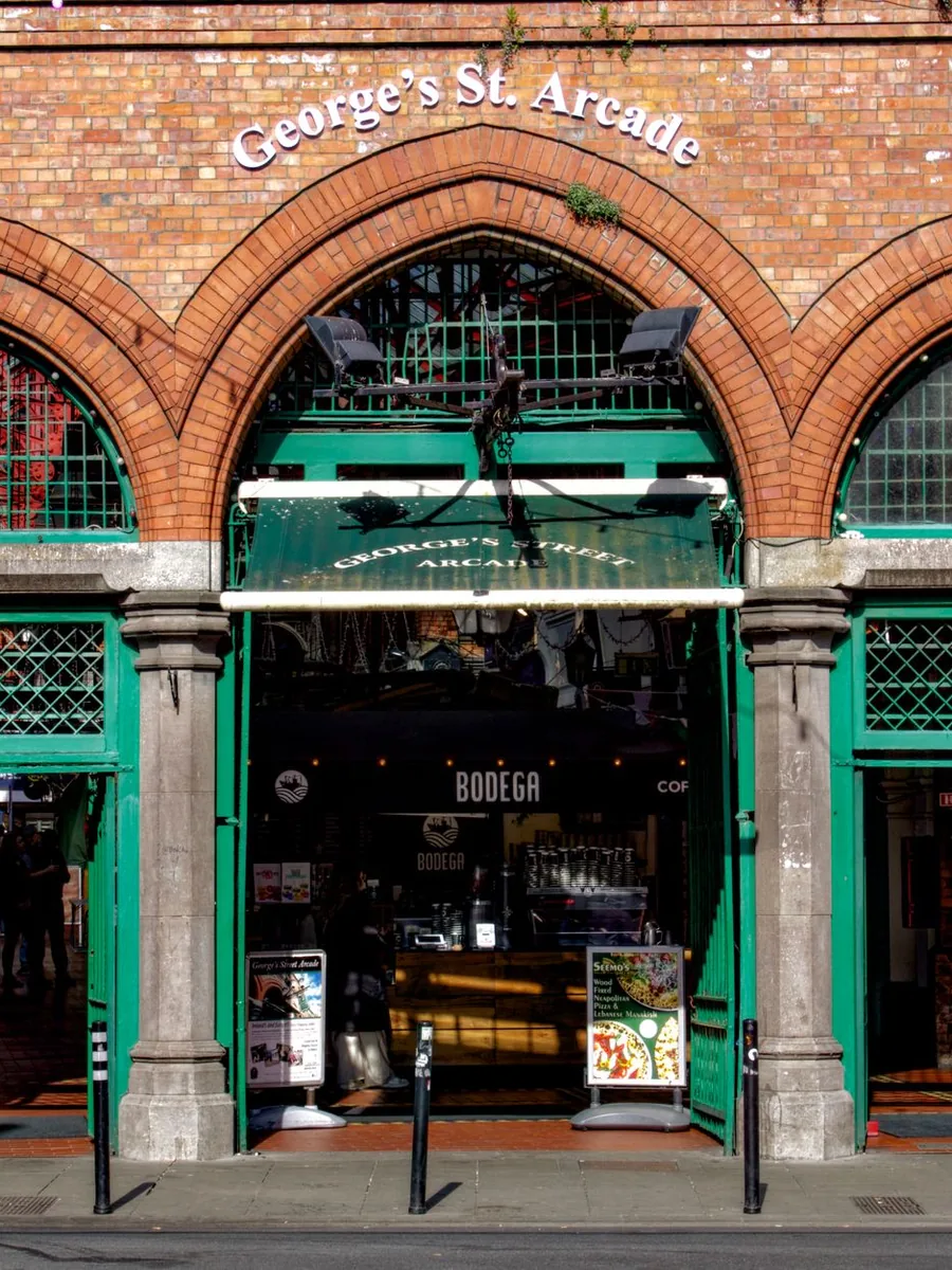 L'ingresso ad arco in mattoni rossi della George's Street Arcade a Dublino, con porte e colonne dipinte di verde